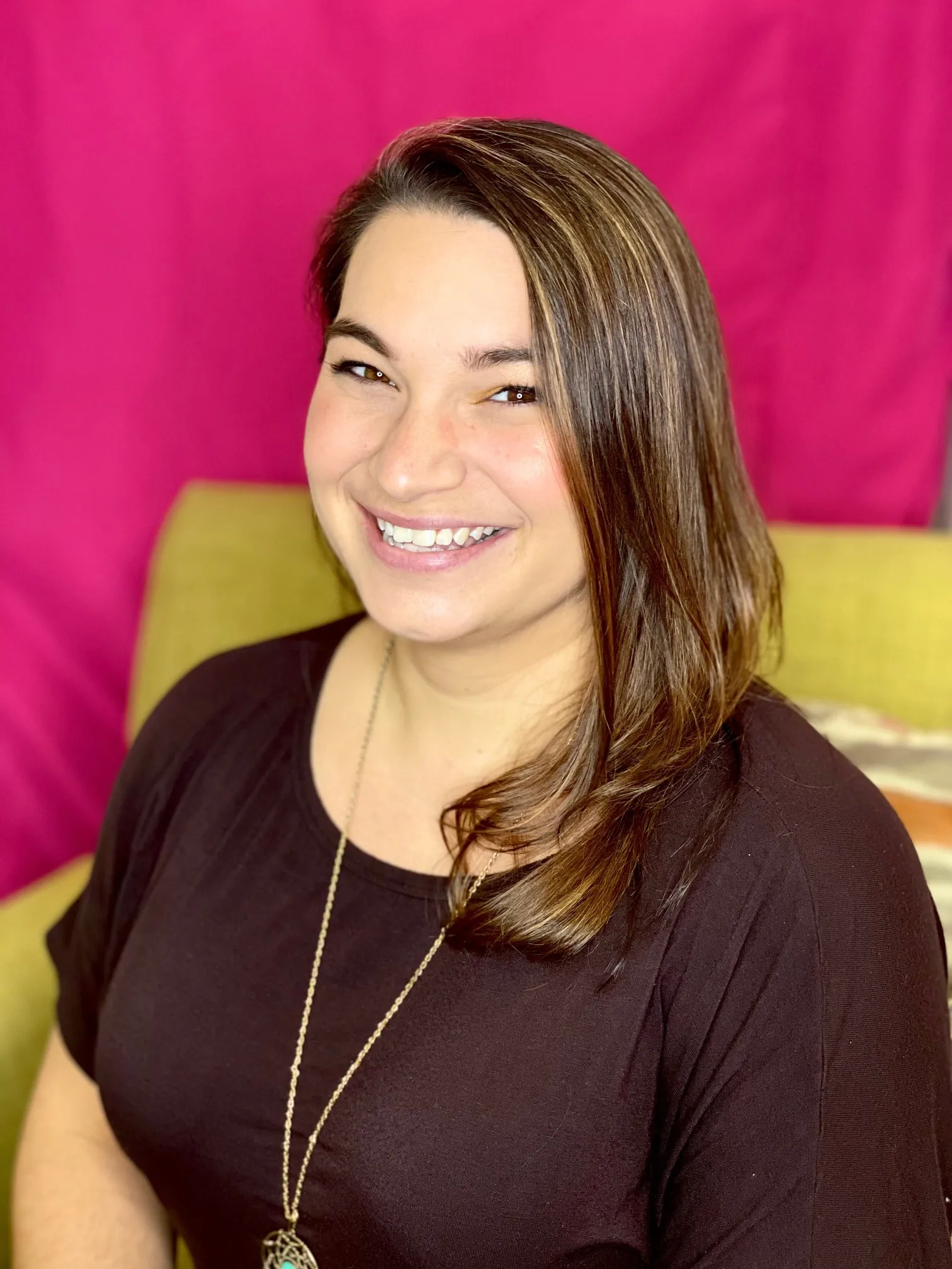 a woman sitting in a chair smiling for the camera