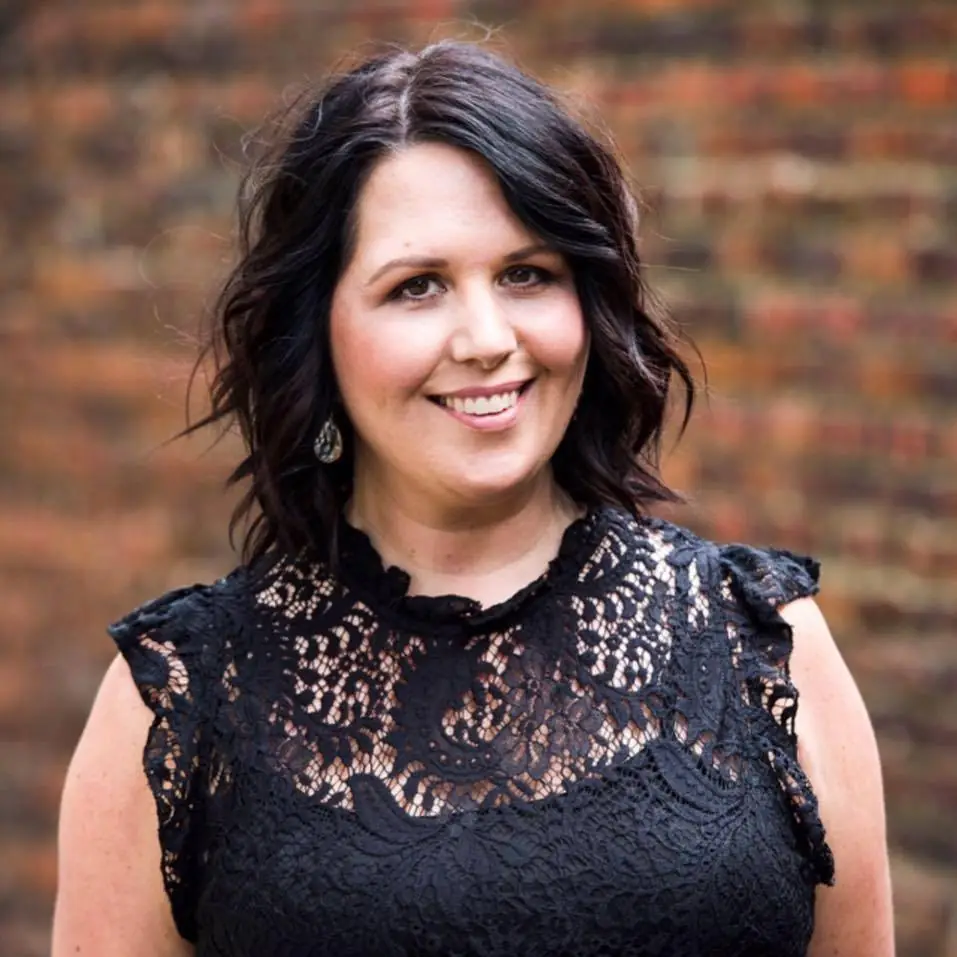 a woman standing in front of a brick wall